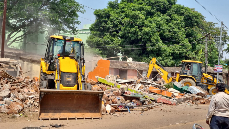 A bulldozer runs over the illegal house